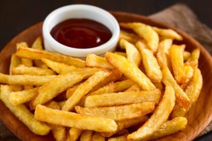 Plate covered in French fries and a small cup of ketchup