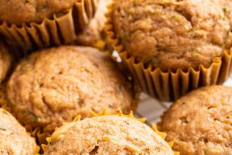 Multiple zucchini muffins on a cooling rack.