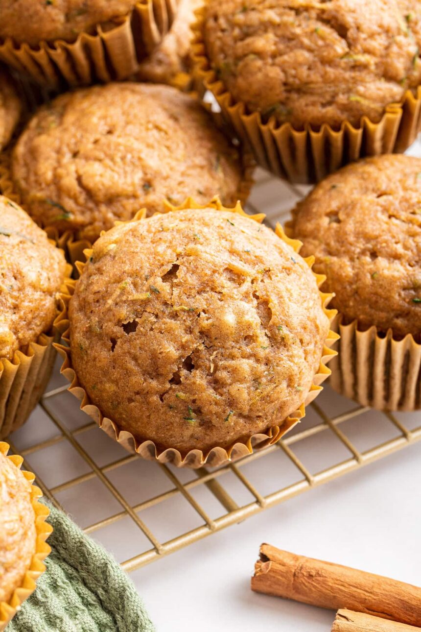 Multiple zucchini muffins on a cooling rack.