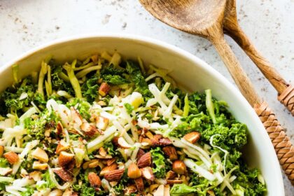 A large bowl of kale crunch salad topped with crushed almonds.