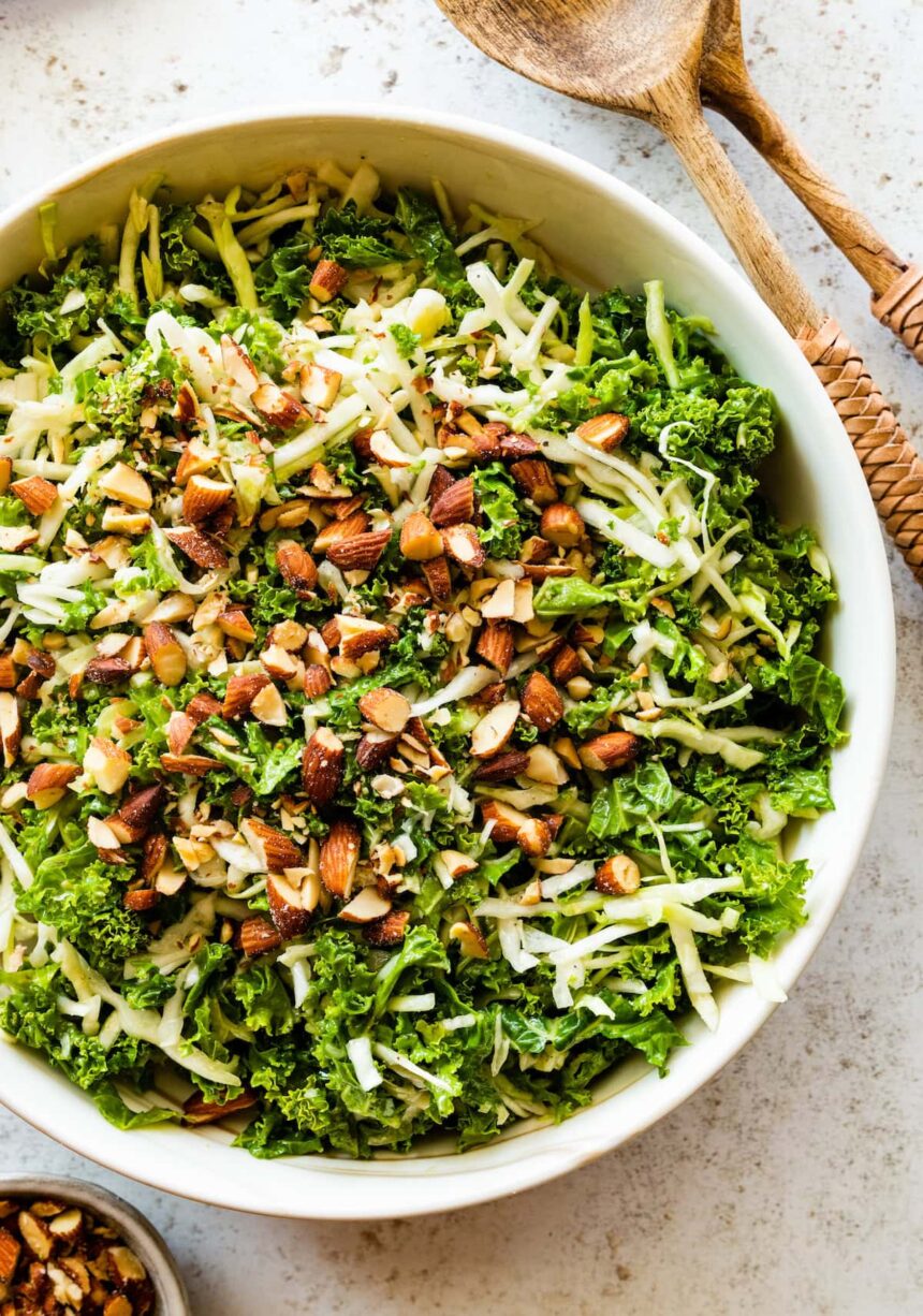 A large bowl of kale crunch salad topped with crushed almonds.