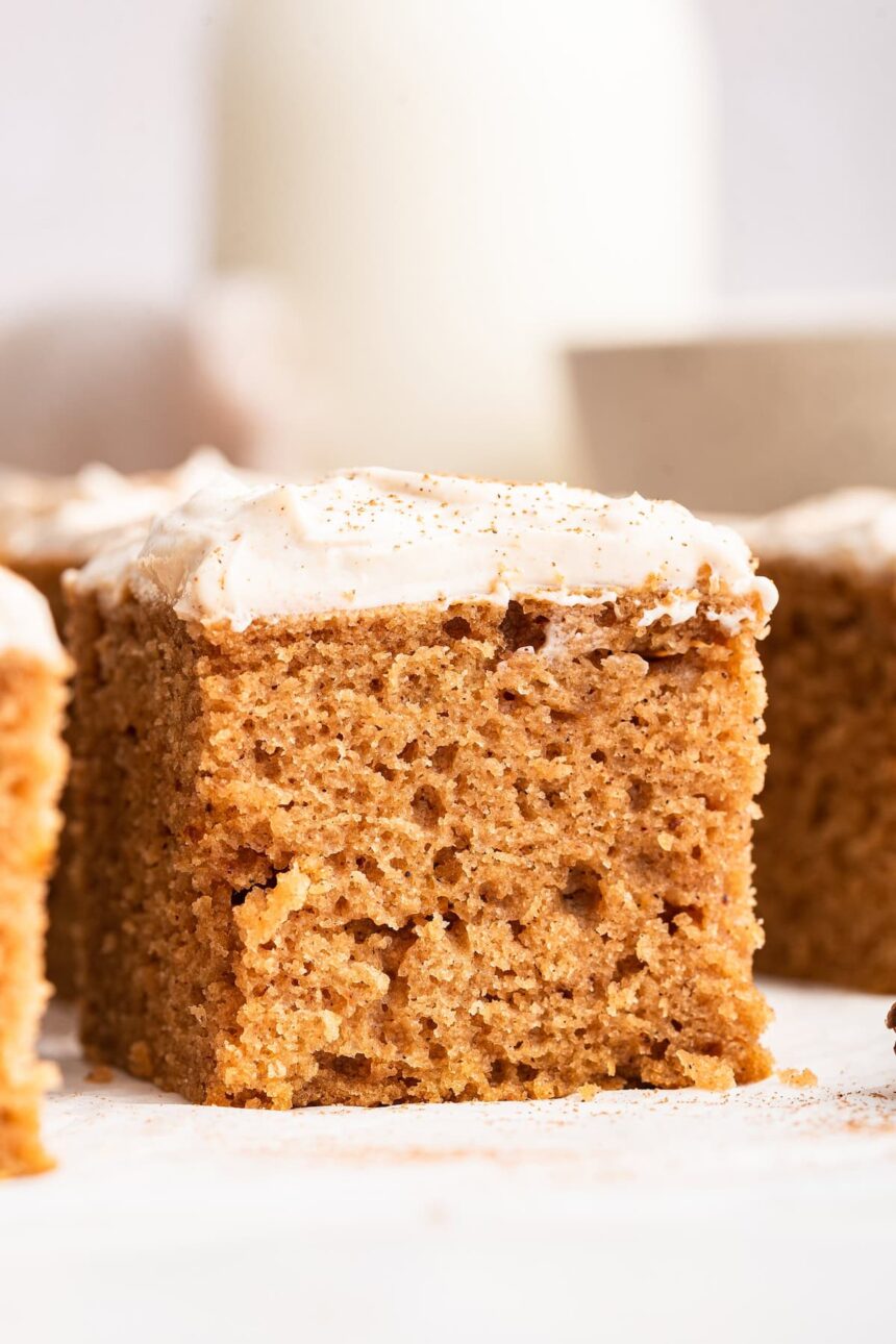 A slice of applesauce cake topped with a cinnamon cream cheese frosting.