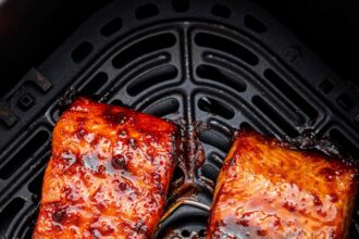 Two date glazed salmon filets in an air fryer basket.