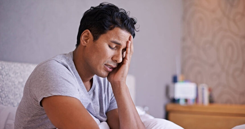 Man sitting in bed looking tired