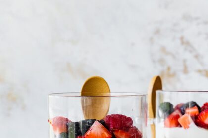 Two glass cups of fruit and yogurt parfaits. The cups are layered with fruit, yogurt, granola, then yogurt again and more fruit on top.