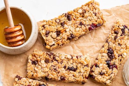 Multiple granola bars with dried cranberries and chocolate chips on parchment paper.