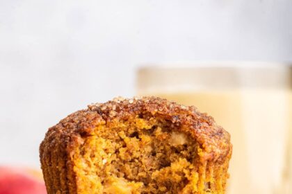 Two apple muffins stacked on one another with the top muffin having a large bite taken from it.