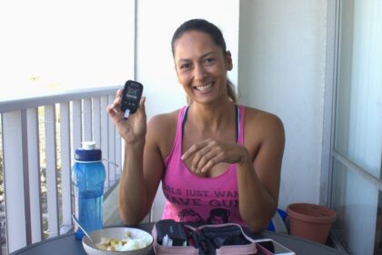 Christel holding a blood sugar meter while eating lunch on the balcony