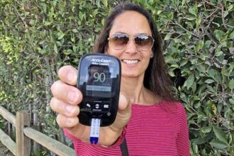 Christel holding a blood glucose monitor showing a 90 mg/dl blood sugar level