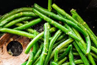 Sautéed Green Beans in a skillet with a wooden spatula.