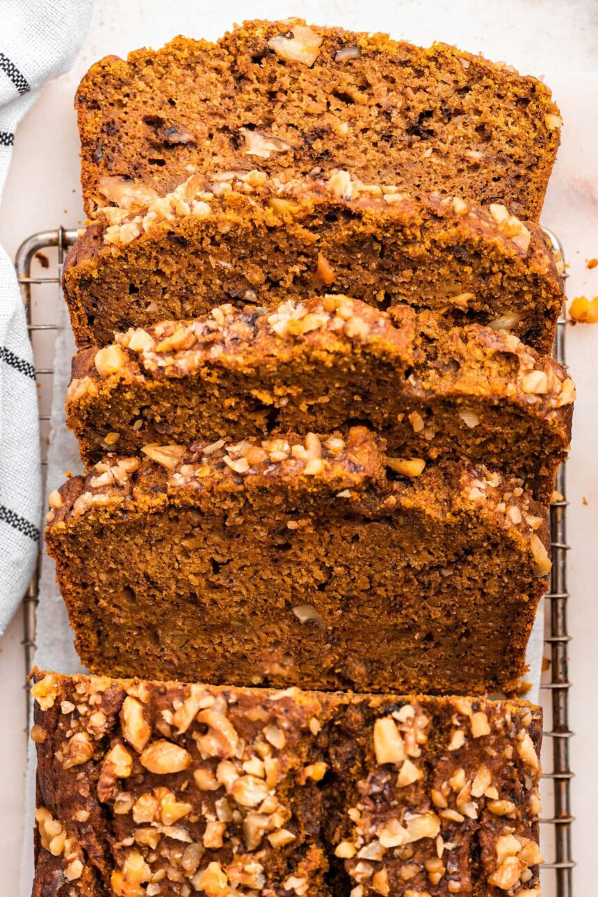 Four slices of pumpkin banana bread lean against one another on a cooling rack.