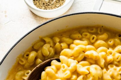 A large pot of cottage cheese mac and cheese with a wooden serving spoon.