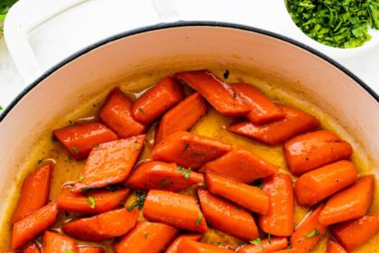 Glazed carrots cooked in a large pot and topped with fresh thyme.