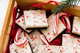 Square peppermint bark pieces stacked on top of each other in a gift box.