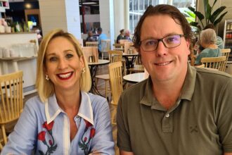 Justine Cain and James Ashman sit behind a white table