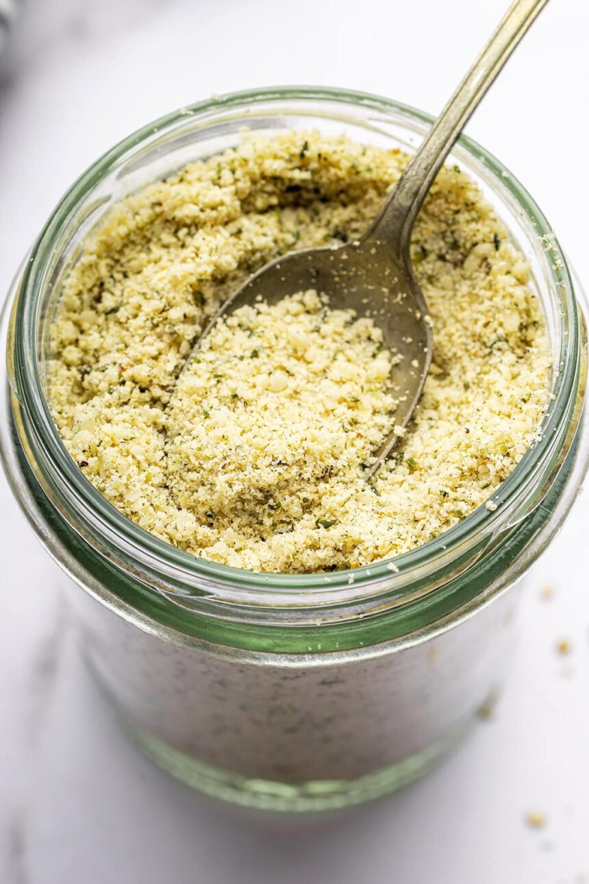 A vegan parmesan cheese made with hemp seeds in a glass mason jar with a metal spoon.