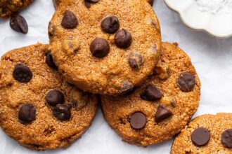 9 flourless peanut butter cookies with chocolate chips spread out on parchment paper.